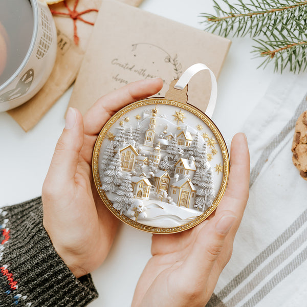 Fehér–arany karácsonyfadísz téli falucskával és templommal